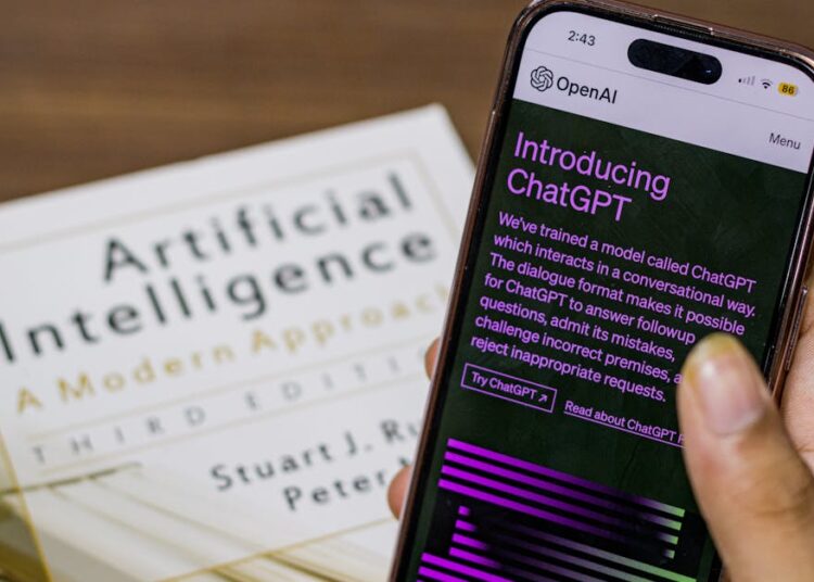 Close-up of a smartphone displaying ChatGPT app held over AI textbook.